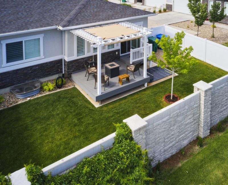A backyard of a suburban USA home with a deck and pergola, aerial view.