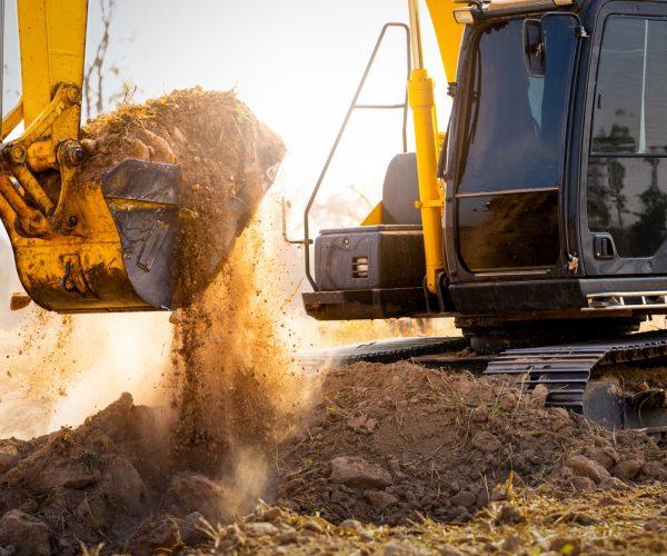 Close-up of excavator at construction site. Backhoe digging soil for earthwork and construction business. Excavating machine at work. Heavy machinery for earth moving and construction site development